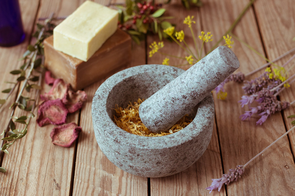mortar and pestle by sopa and herbs and dried flowers
